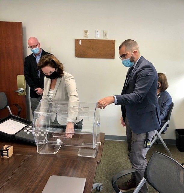 Cannabis lottery simulation at OCR (Cassius Shuman) ELIZABETH M. TANNER, middle, director of the R.I. Department of Business Regulation, demonstrates how the lottery for the medical marijuana dispensary licenses will work. Tanner was at the Office of Cannabis Regulation on Friday with Russ Griffiths, left, a DBR policy analyst, and Matthew Santacroce, the state's cannabis chief. PBN PHOTO/CASSIUS SHUMAN