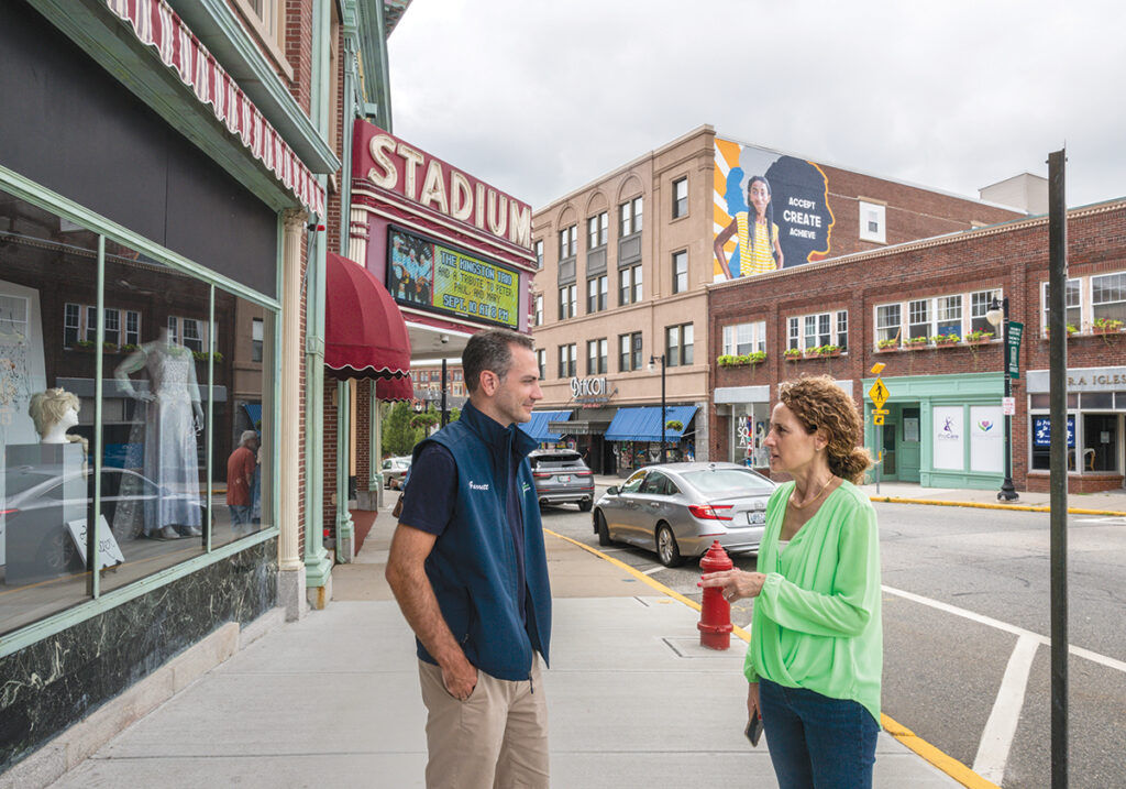 FOCUSED LEADERS: Woonsocket Mayor Lisa Baldelli-Hunt and Garrett Mancieri, director of the Downtown Woonsocket Collaborative, tour some of their favorite downtown spots, including the Stadium Theatre Performing Arts Center in Monument Square. The pair agree there should be a focus on getting more people to live in the downtown. / PBN PHOTO/MICHAEL SALERNO