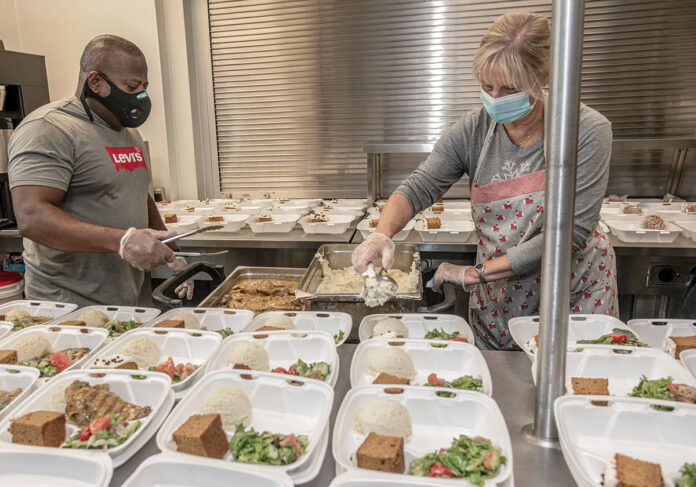 DISHING OUT MEALS: Douglas Spikes, kitchen manager, and volunteer Kathy Block prepare meals for guests at social services nonprofit Amos House in Providence. / PBN PHOTO/MICHAEL SALERNO DISHING OUT MEALS: Douglas Spikes, kitchen manager, and volunteer Kathy Block prepare meals for guests at social services nonprofit Amos House in Providence. / PBN PHOTO/MICHAEL SALERNO
