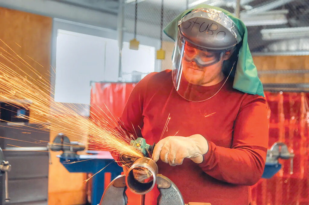 WORKING MODEL: General Dynamics Electric Boat is among the local employers to take advantage of job training through the Westerly Education Center and the Community College of Rhode Island. Above, Michael Stuba trains for a job as a pipe fitter at Electric Boat in 2018. Some panelists see the program as a model for other industries. PBN FILE PHOTO/BRIAN MCDONALD