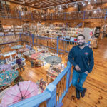 PERFECT FIT: Jay Santiago, who owns the Imagine Gift Store with his wife, Michelle, stands on the upper landing of the second floor of the three-story shop located in the former Lyric Theater building in Warren. Michelle Santiago says the shop, with its quirky items, fun atmosphere and interactive murals, fits seamlessly into the town’s creative energy. / PBN PHOTO/MICHAEL SALERNO