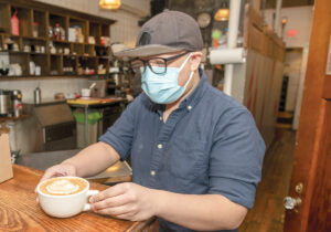 PIECE OF THE ACTION: Christian Rakotoarisoa, one of the worker-owners at White Electric in Providence, serves a latte at the coffee shop.  PBN FILE PHOTO/MICHAEL SALERNO 