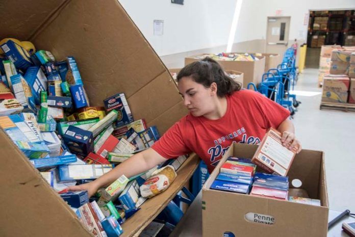 HELPING HAND: Ashley Armstrong of Warwick sorts donated foods at the Rhode Island Community Food Bank. It was Armstrong's first day volunteering at the food bank, part of the charitable work she needs to do in order to make her confirmation at Saints Rose and Clement parish in Warwick. / PBN PHOTO/ MICHAEL SALERNO