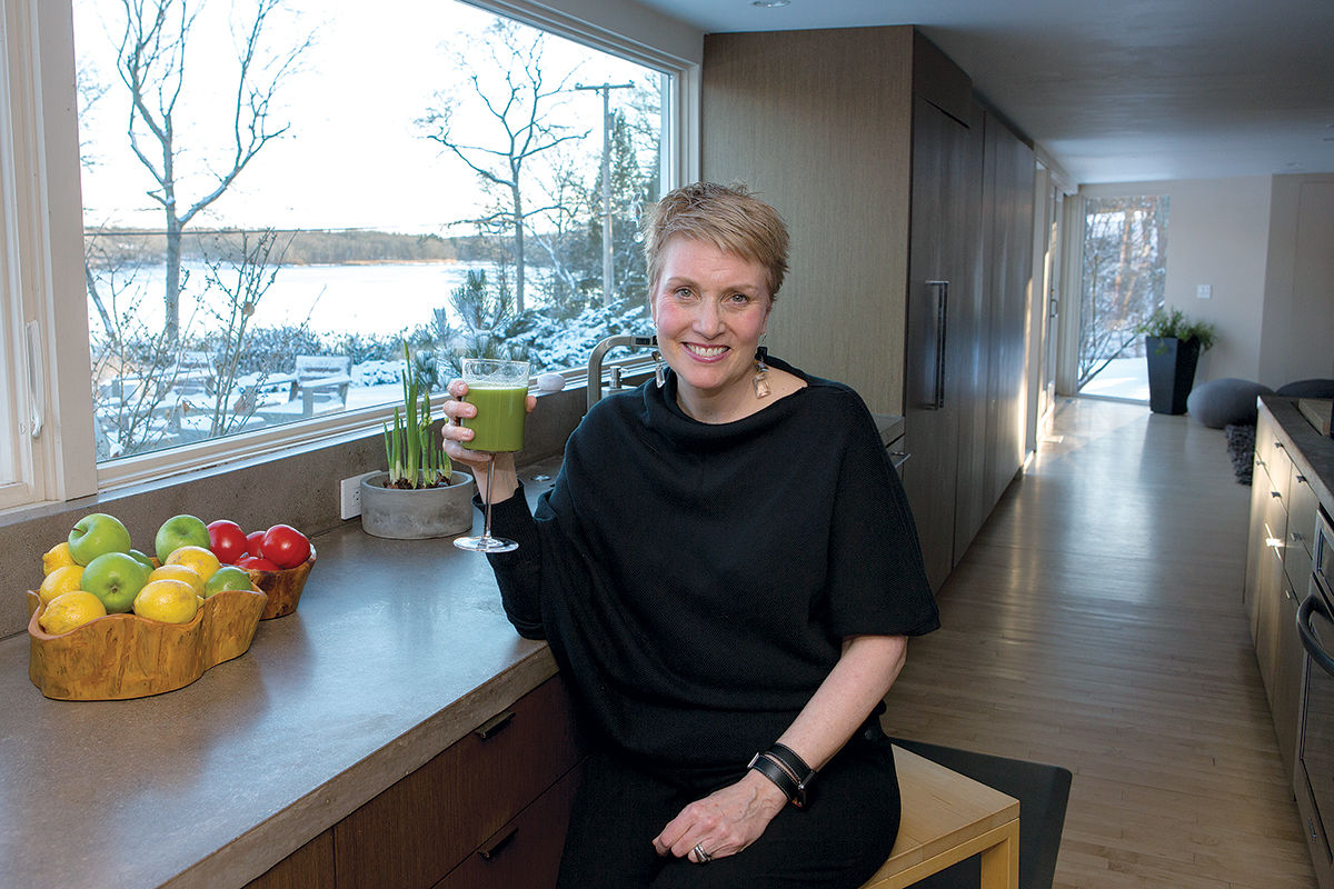 COLD CURE: Katie McDonald, corporate health coach and owner of bnourished, sits at her kitchen counter enjoying a green juice, a remedy/prevention for winter colds. / PBN PHOTO/KATE WHITNEY LUCEY