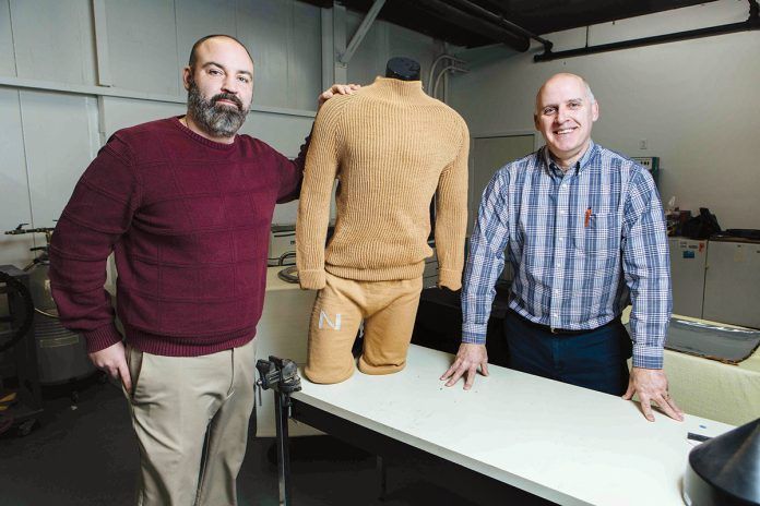 CUTTING-EDGE CLOTHES: Response Technologies President Ed Bard, left, and CEO David Pettey display a garment made using the company’s 3D textile process, which required no cutting or sewing. Produced for the U.S. Navy, the garment could be made to be fire-resistant and embedded with smart features.  / PBN PHOTO/RUPERT WHITELEY