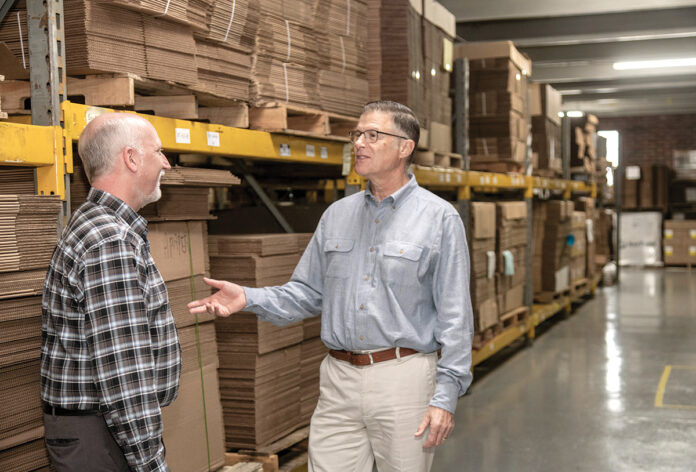 PAPER PUSHERS: David Spencer, right, CEO of Atlantic Paper & Supply, talks with sales representative Sean Borek. Spencer runs the company with his wife, Lisa, whose grandfather started the business in the 1940s. / PBN PHOTO/MICHAEL SALERNO PAPER PUSHERS: David Spencer, right, CEO of Atlantic Paper & Supply, talks with sales representative Sean Borek. Spencer runs the company with his wife, Lisa, whose grandfather started the business in the 1940s. / PBN PHOTO/MICHAEL SALERNO
