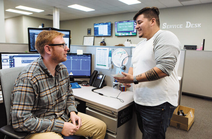 SHOP TALK: Vertikal6 service desk apprentices Steven Walsh, left, and Dylan Herrera share a conversation in the company’s office. / PBN PHOTO/RUPERT WHITELEY SHOP TALK: Vertikal6 service desk apprentices Steven Walsh, left, and Dylan Herrera share a conversation in the company’s office. / PBN PHOTO/RUPERT WHITELEY