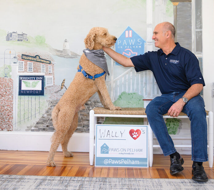 HOUND HOSPITALITY: Chris Bicho, president of Landings Real Estate Group, which owns the Newport inn Paws on Pelham, greets Wally, a goldendoodle, in the lobby. / PBN PHOTO/DAVE HANSEN HOUND HOSPITALITY: Chris Bicho, president of Landings Real Estate Group, which owns the Newport inn Paws on Pelham, greets Wally, a goldendoodle, in the lobby. / PBN PHOTO/DAVE HANSEN