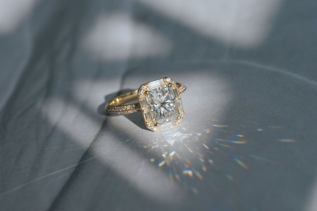 art deco engagement rings - vintage aethetic yellow gold engagement ring featuring a moissanite radiant centre and baguette halo