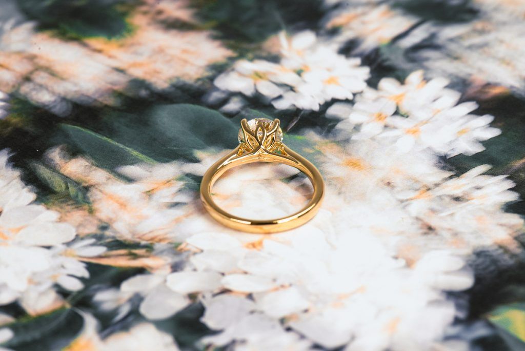 Custom vs Ready-Made Engagement - photo of the underside of an engagement ring showcasing petal prongs and a hidden round diamondin the middle of a petal prong abstract flower background