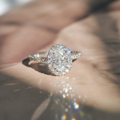 White gold, oval cut engagement ring with natural round diamonds in a halo