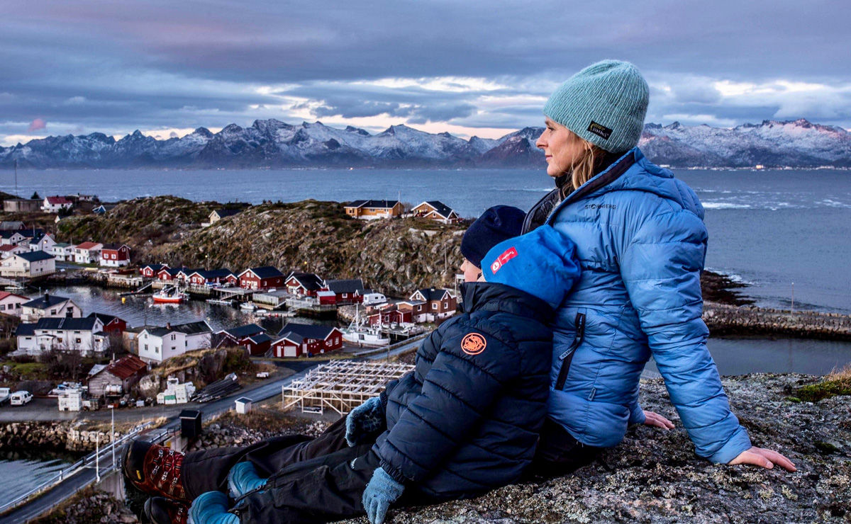 Elin og sønnene med fiskeværet i bakgrunnen