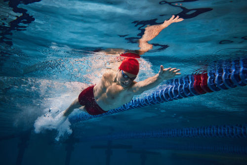 Junger Mann, Schwimmer im Bewegungstraining im Schwimmbad / Hallenbad