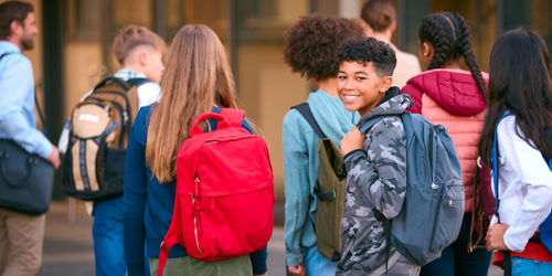 Portrait männlicher Sekundarschüler oder Schüler im Außenschulgebäude mit Lehrern und Schülern.