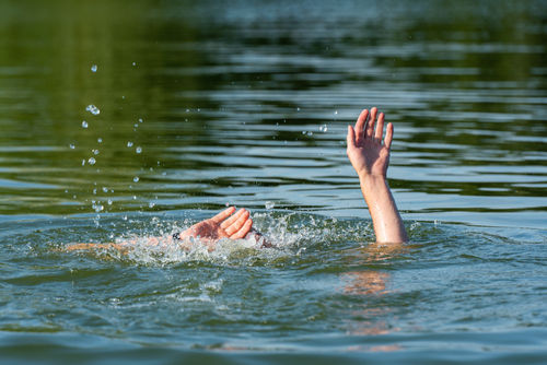 Hände eines ertrinkenden Mannes über Wasser, der Hilfe braucht.