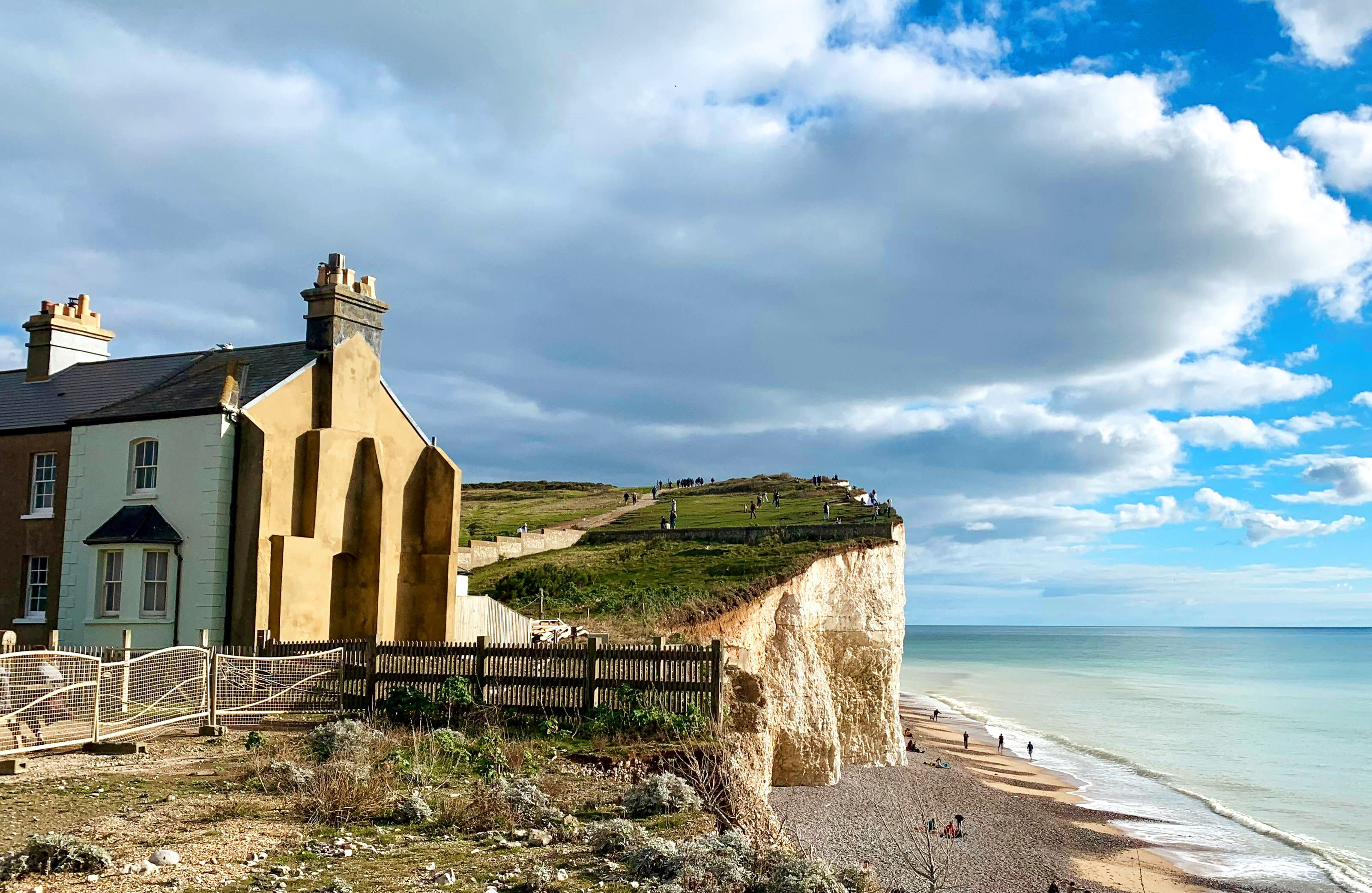 A UK coastal residential street with a clean rendered house exposed to the seafront