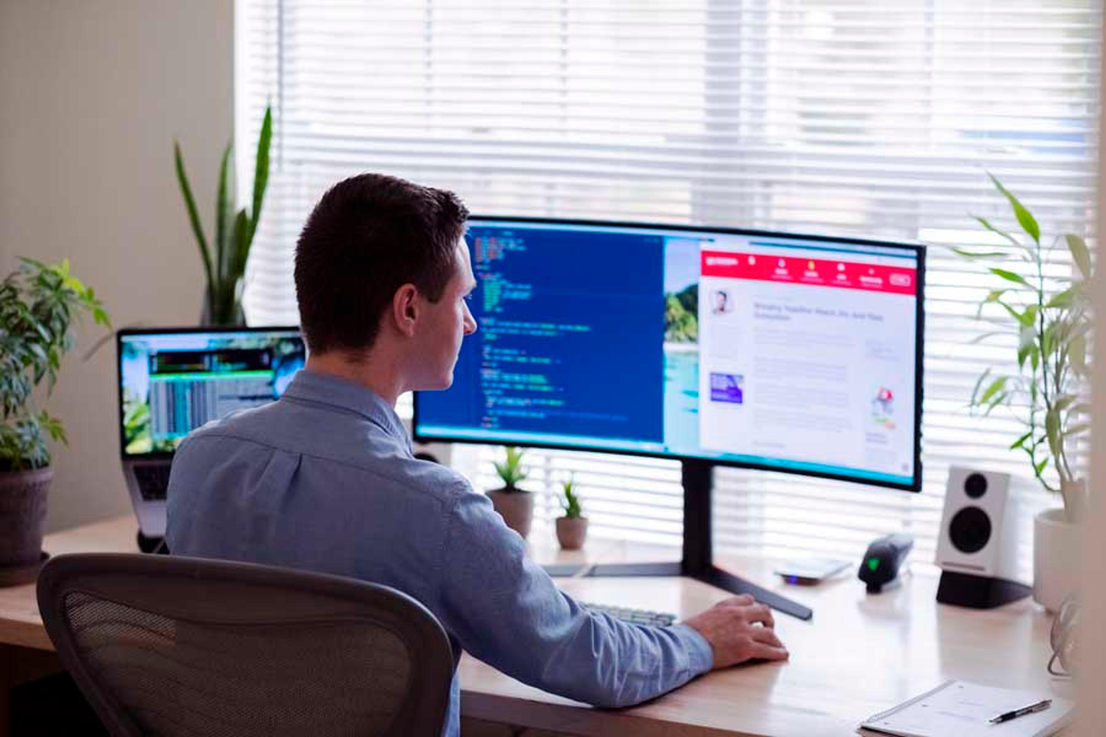 Man sitting at desk and looking at a double computer monitor