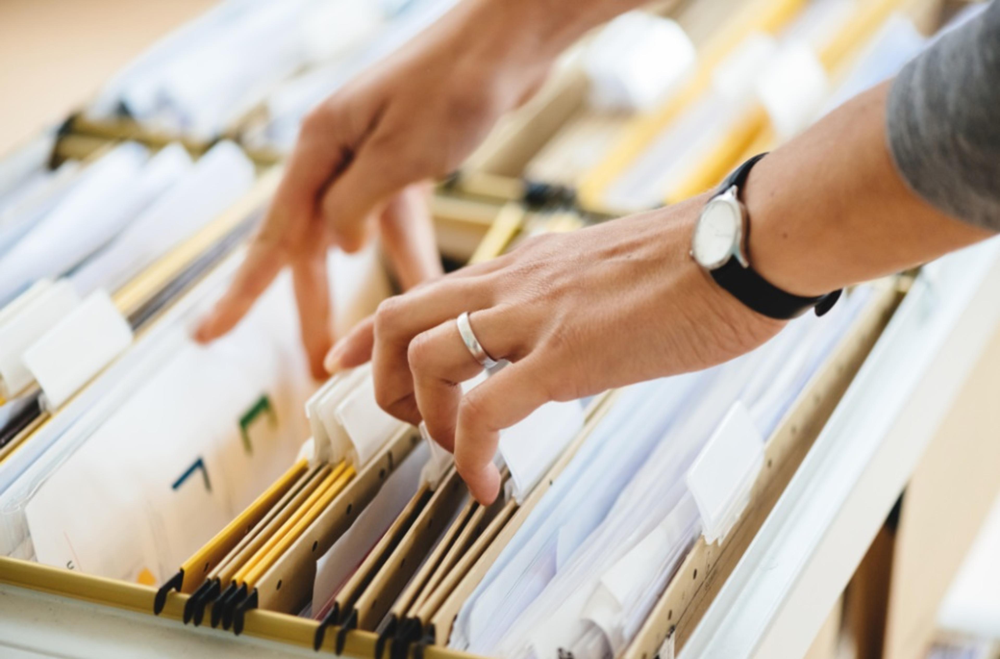Person rifling through a file folder drawer