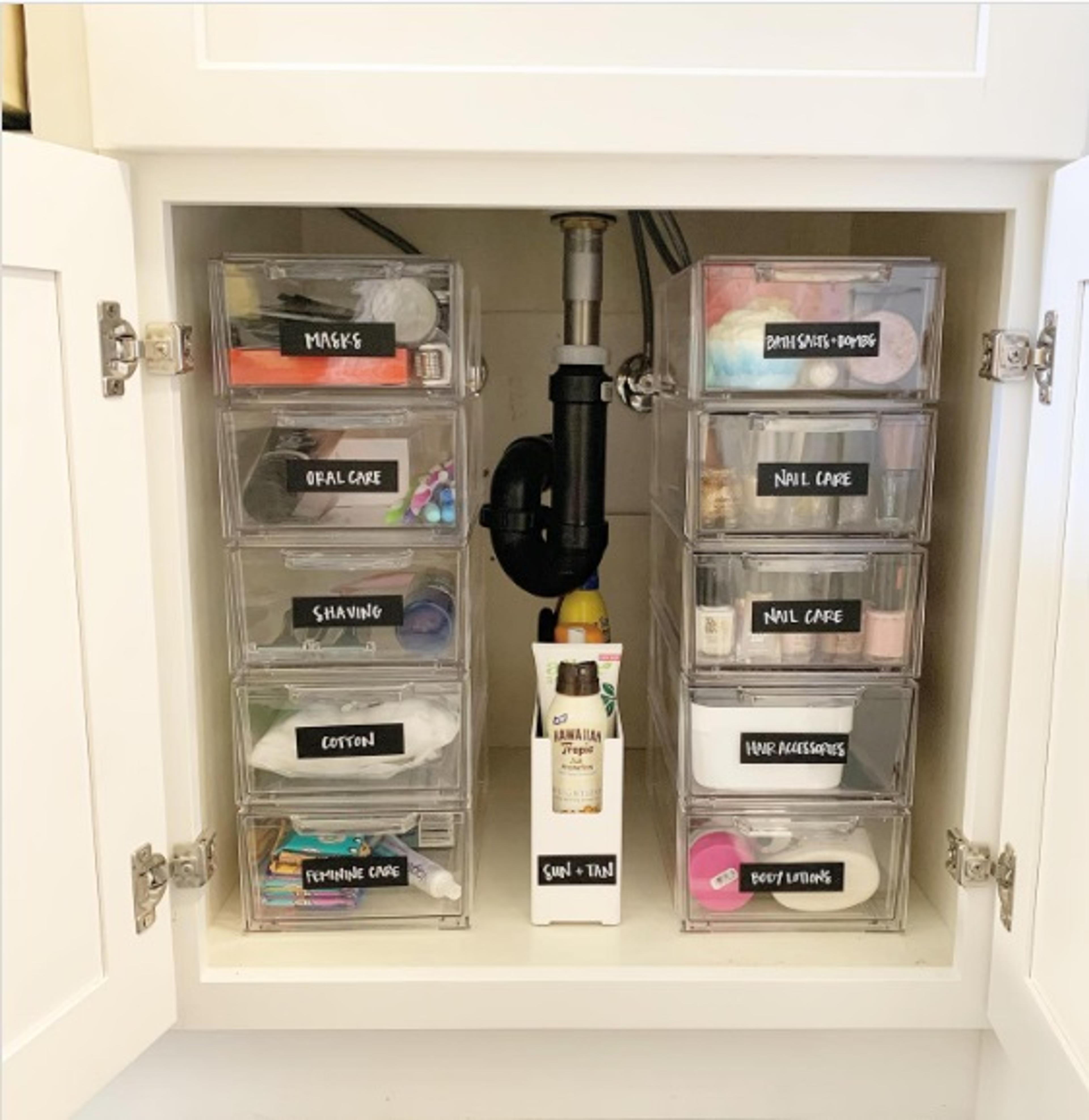 Clear stackable bins filled with product under a bathroom sink