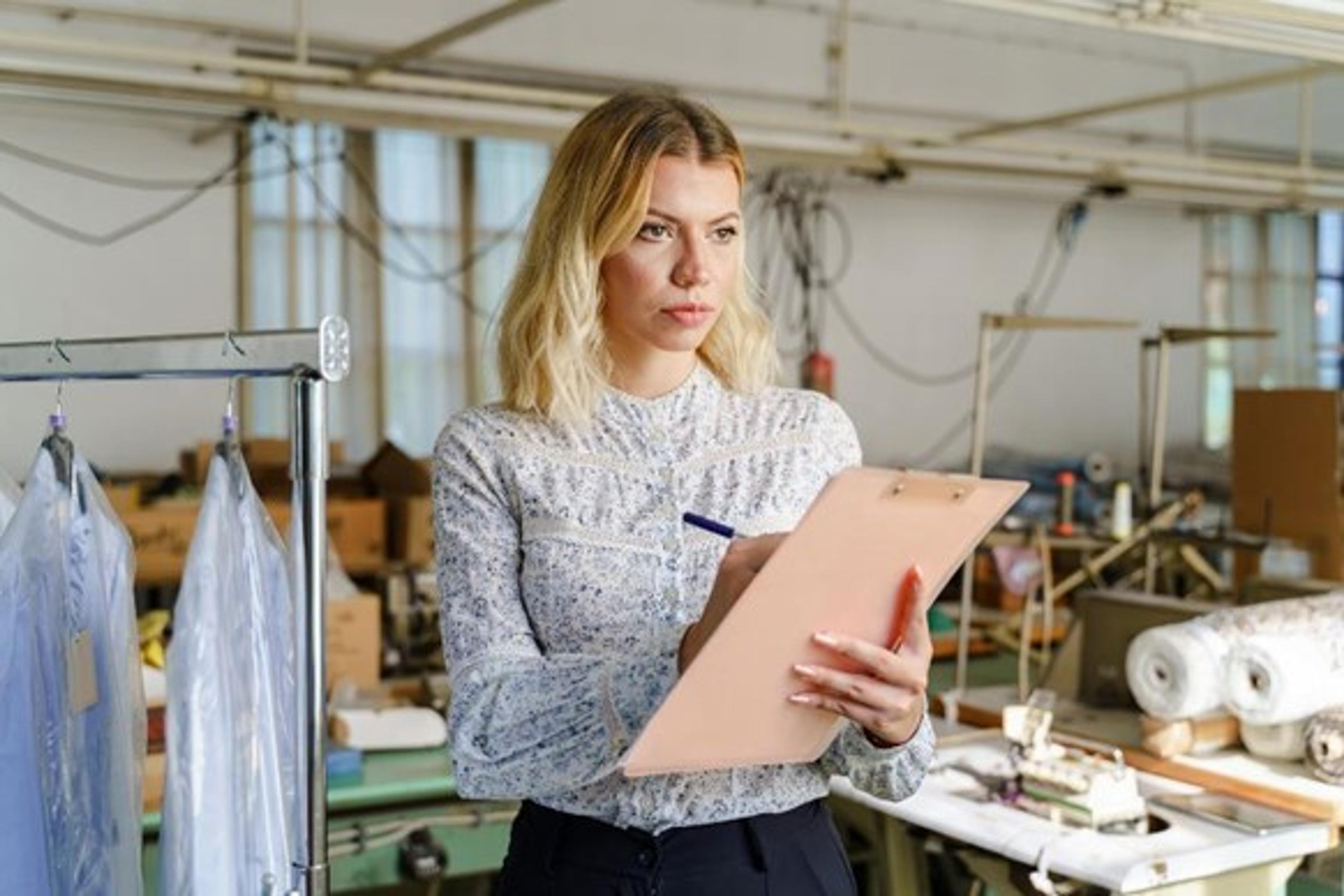 the owner of a clothing store is holding a clipboard