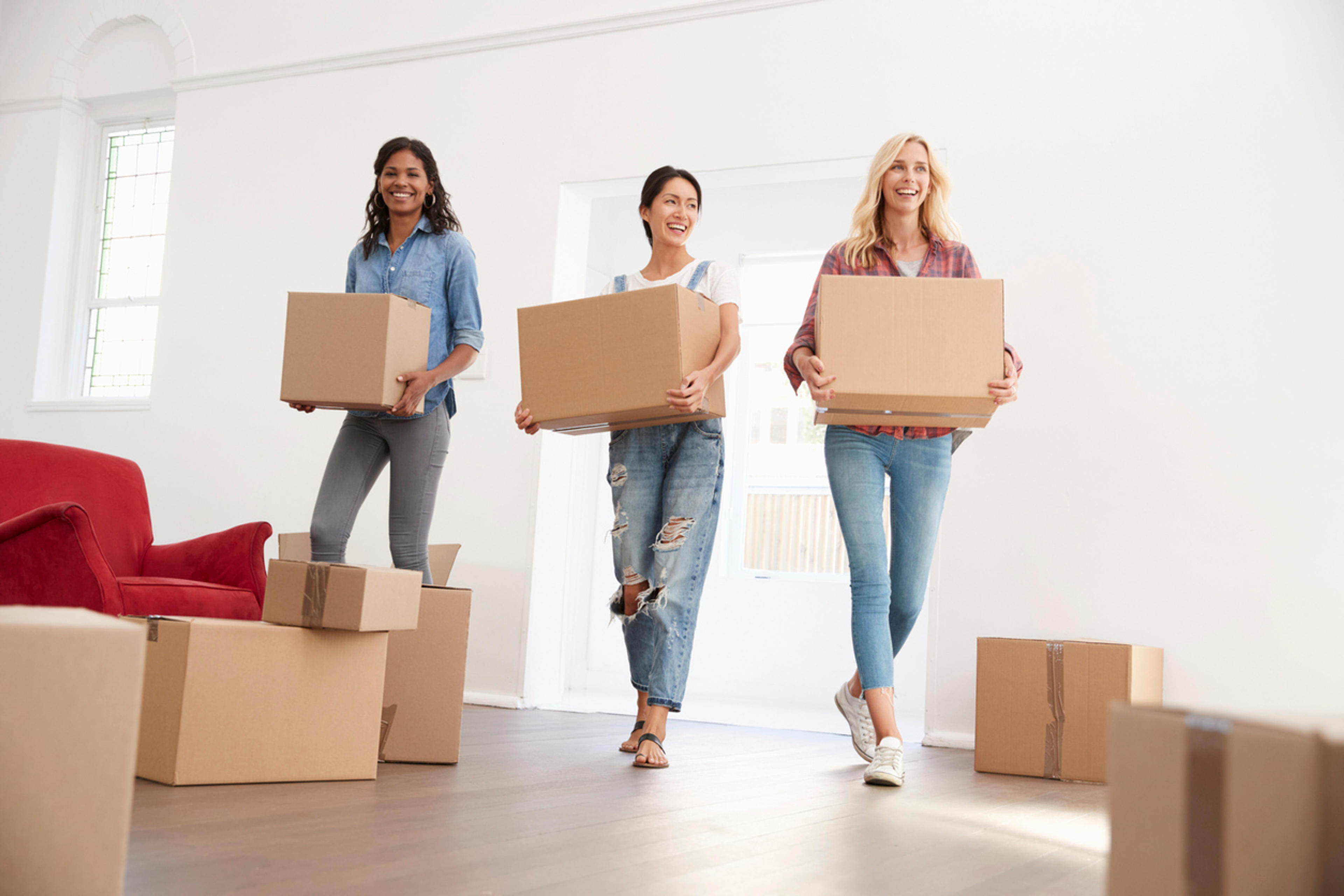 Three Female Friends Carrying Boxes Into New Home On Moving Day