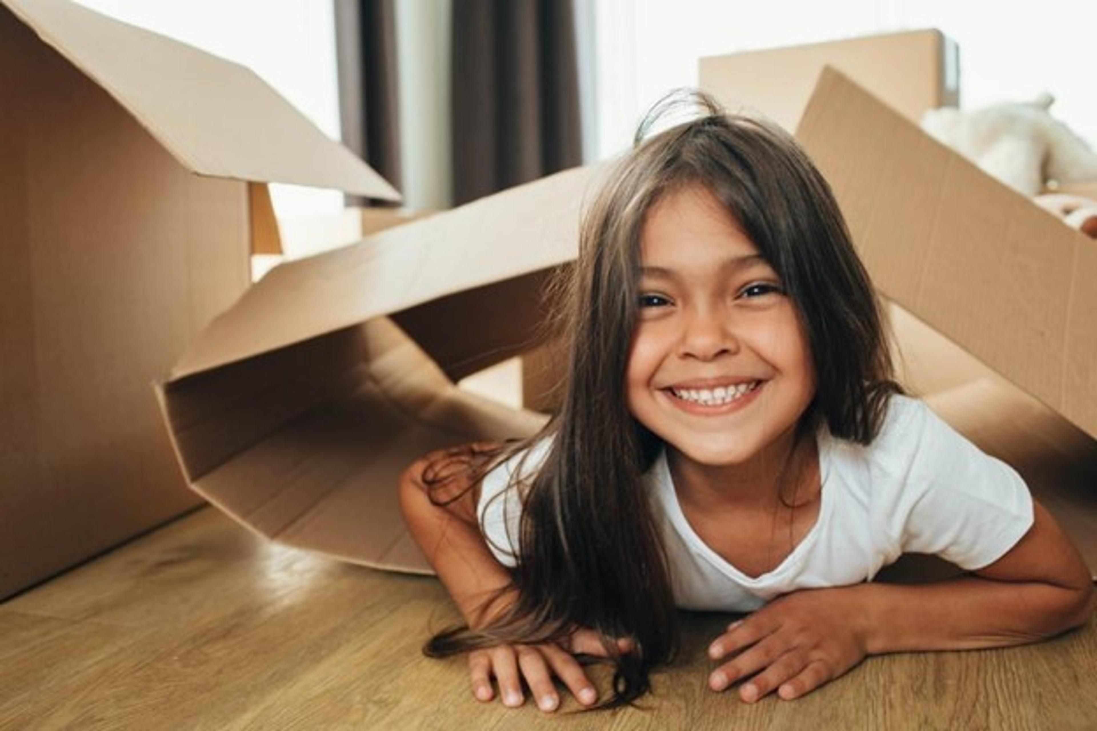 Smiling child playing with empty moving boxes