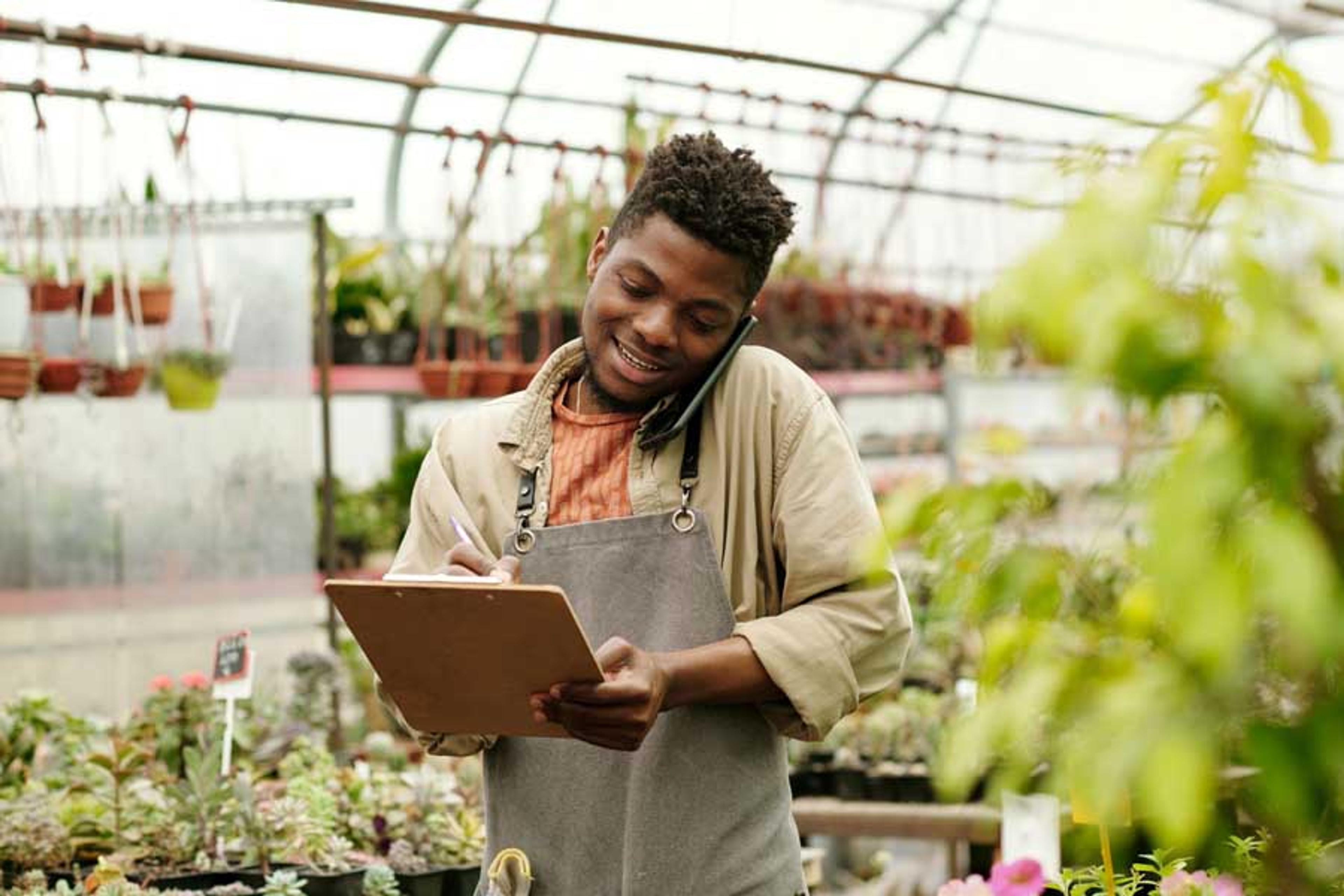 Manager using an iPad in a greenhouse to track inventory