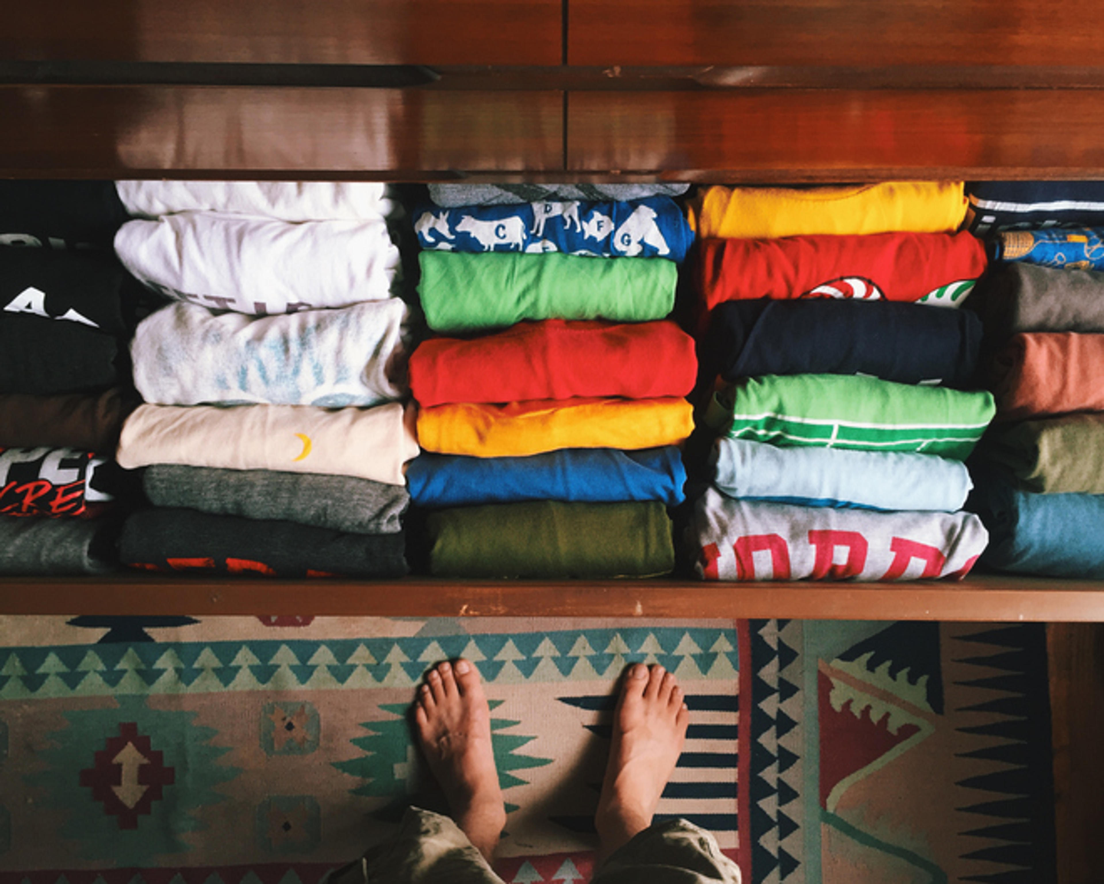 T-shirts folded in a drawer, designs facing outward.