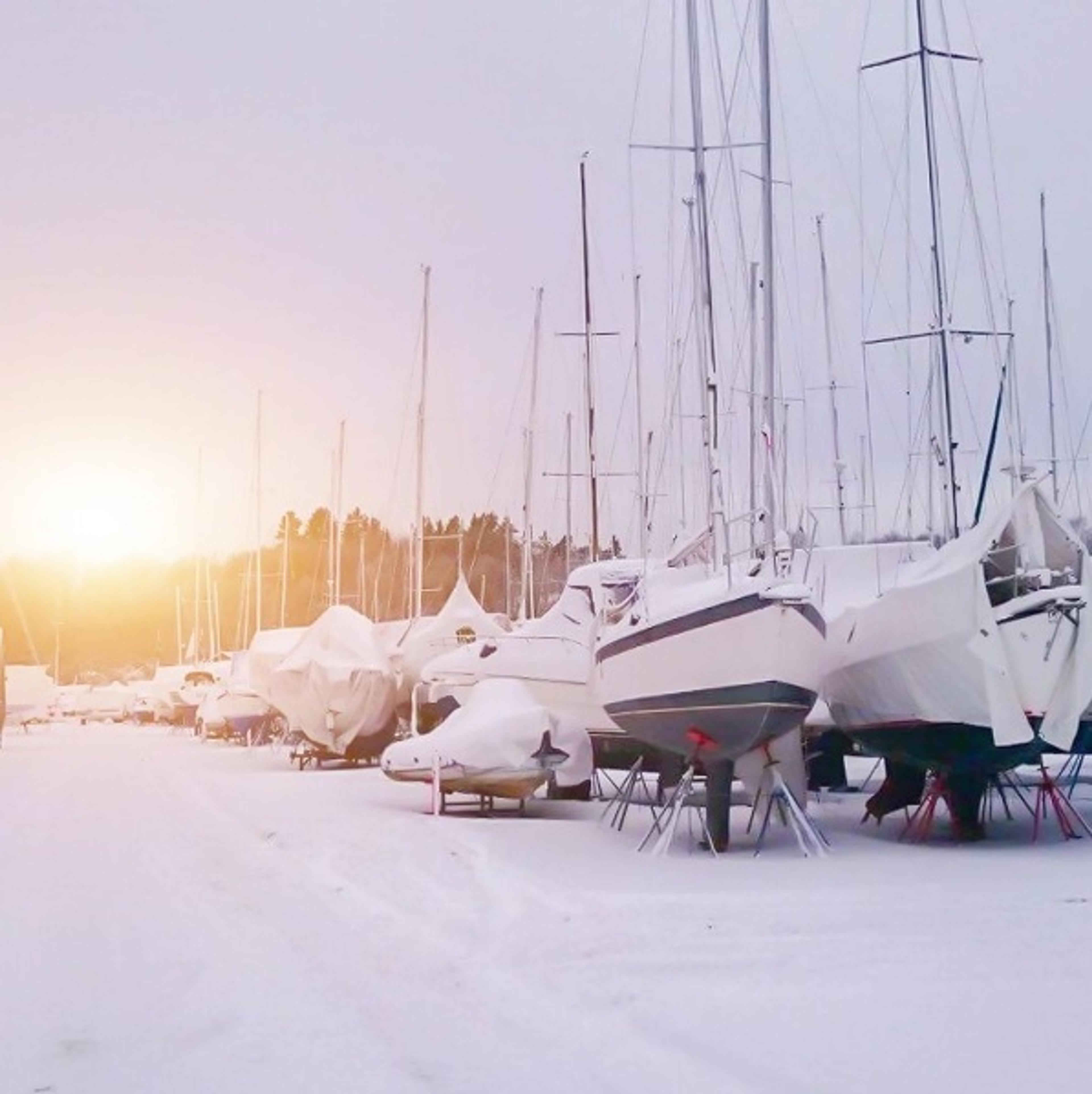 Rows of covered boats stored outside in the snow