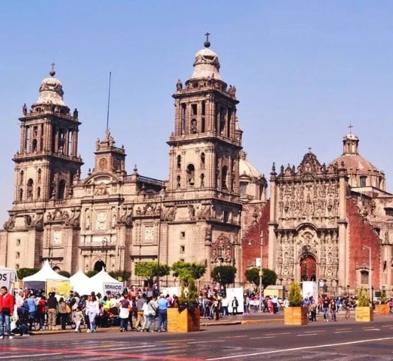Mexico City Metropolitan Cathedral with a lively crowd and market tents in the foreground on a sunny day