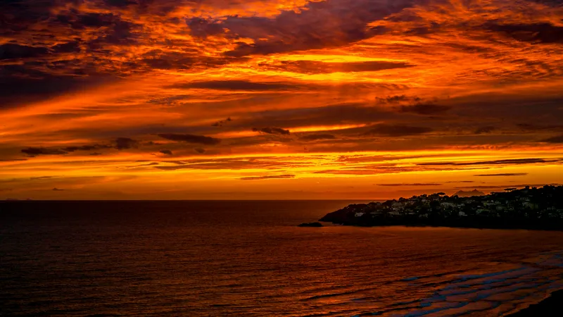 Sunset over Gaeta beach with vibrant orange sky and silhouetted town