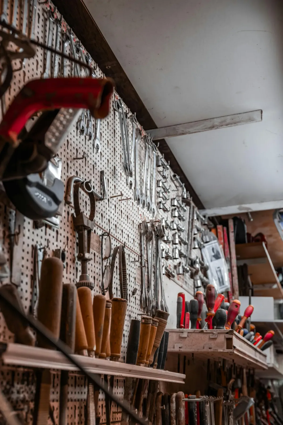 A wall of hand tools neatly organized on hangers in a maintenance workshop