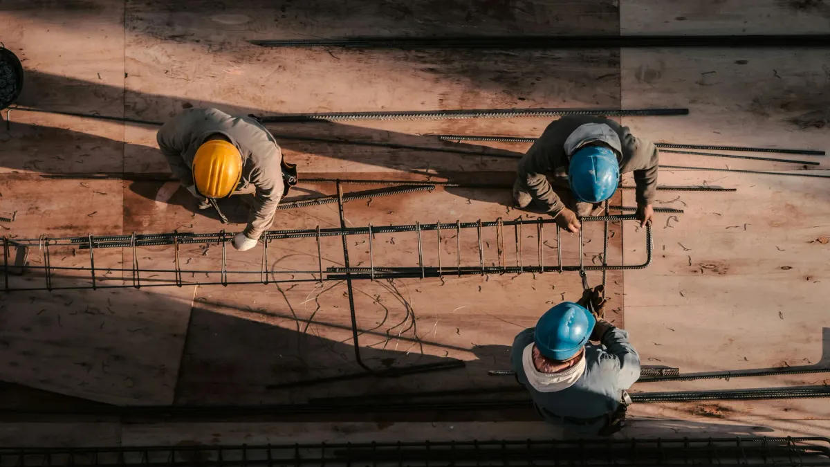 An overhead view of wooden roof framing with hard hats hanging from the beams