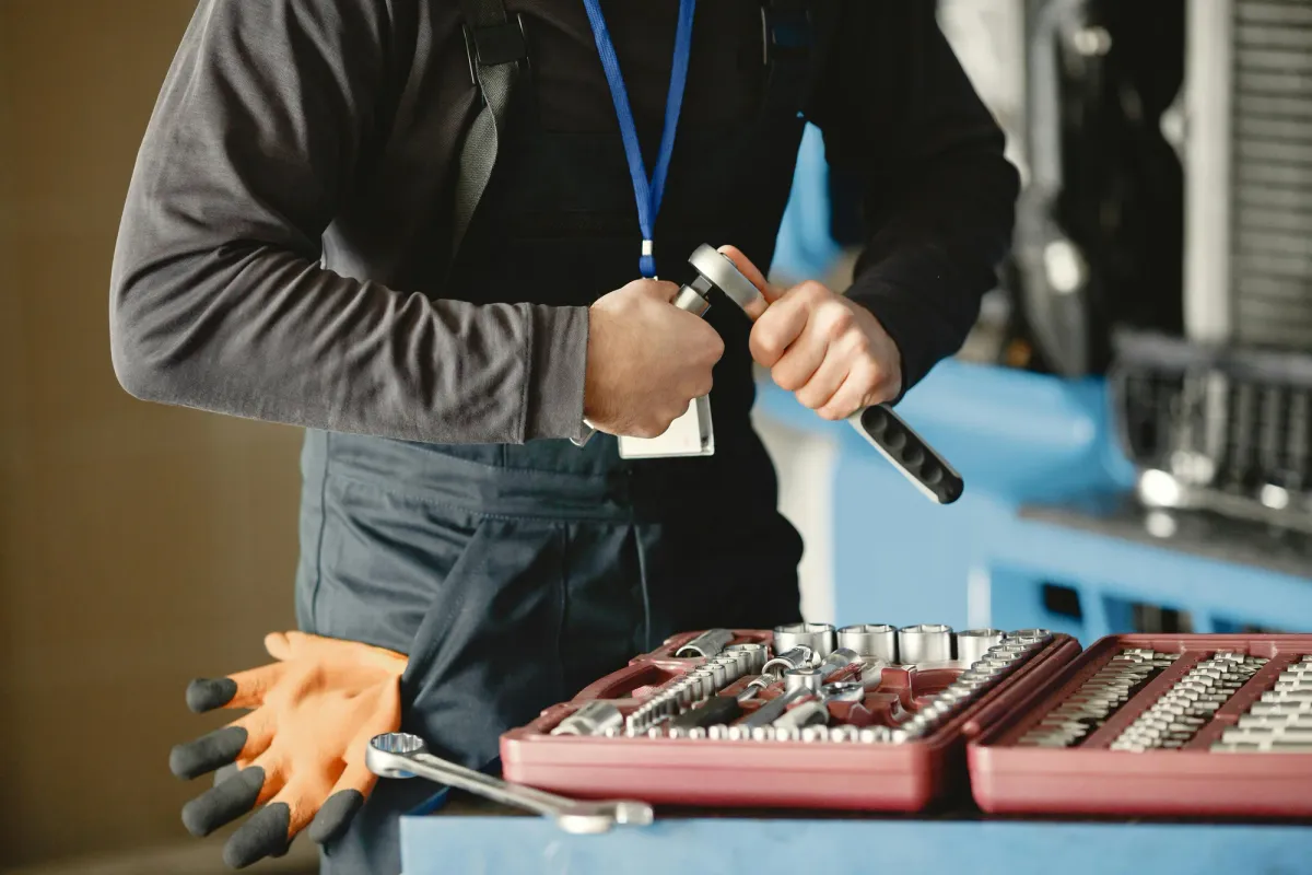A facilities worker at a workbench sorting through a tray of wrenches and hand tools