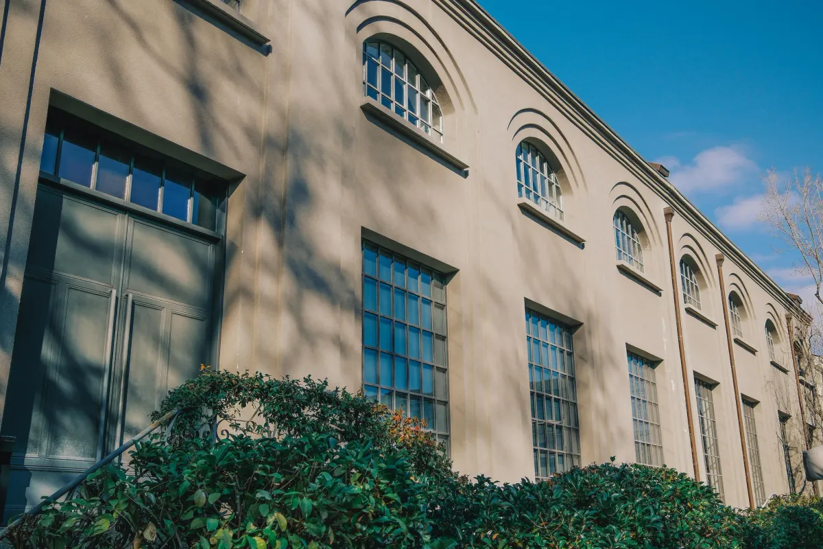 The brick exterior of an older institutional building with tall arched windows
