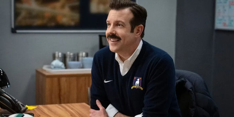 Ted Lasso (Jason Sudeikis) sits at his desk in Ted Lasso