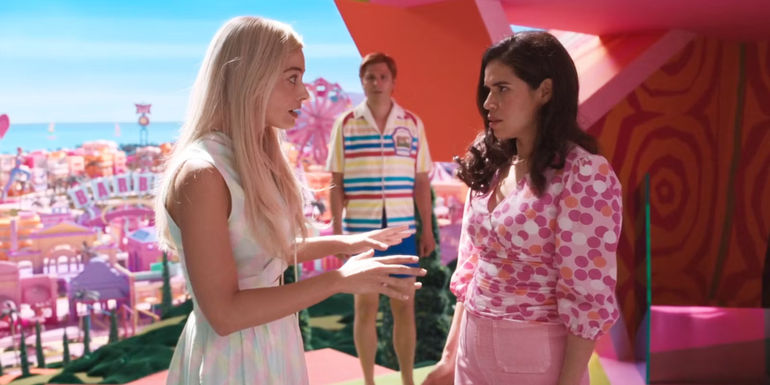 Margot Robbie's Barbie expressing an idea to America Ferrera's Gloria in front of Michael Cera's Allan in Barbie