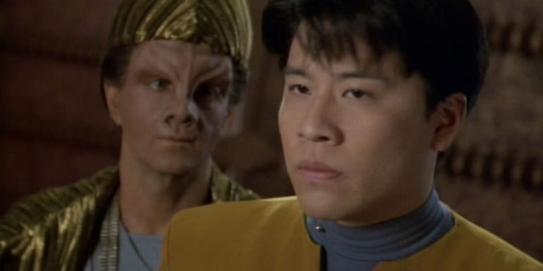 harry kim glares into the middle distance with cool hat alien behind him