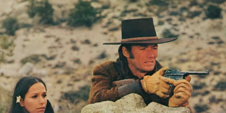 Joe points his pistol from behind a rock in Joe Kidd