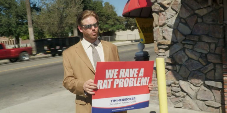 Tim Heidecker holding up a sign in Mister America