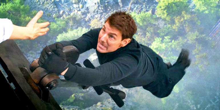 Tom Cruise hanging onto a train hitch in Mission: Impossible - Dead Reckoning Part One.