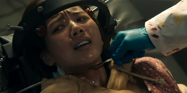 Su-na trapped on a hospital bed with a blade close to her throat