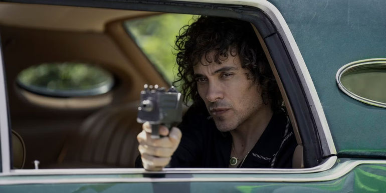 Martin Rodriguez as Jorge Rivi Ayala-Rivera point a submachine gun out of a window in Griselda.