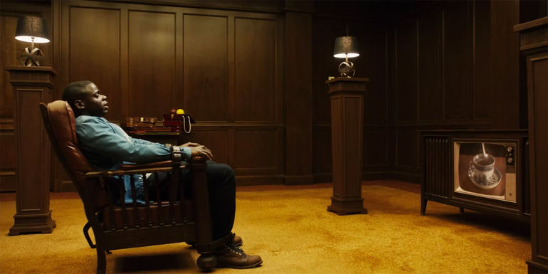 Chris (Daniel Kaluuya) restrained in a chair in front of an old television in Get Out