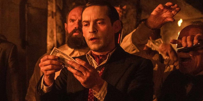James (Tobey Maguire) looks at counterfeit money in Babylon
