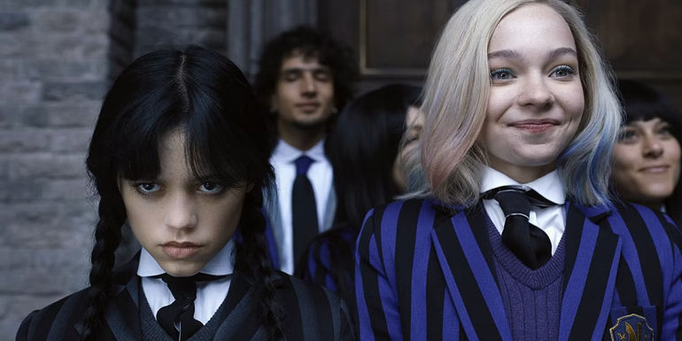 Wednesday (Jenna Ortega) looking grim and Enid (Emma Myers) looking delighted outside Nevermore in Netflix's Wednesday