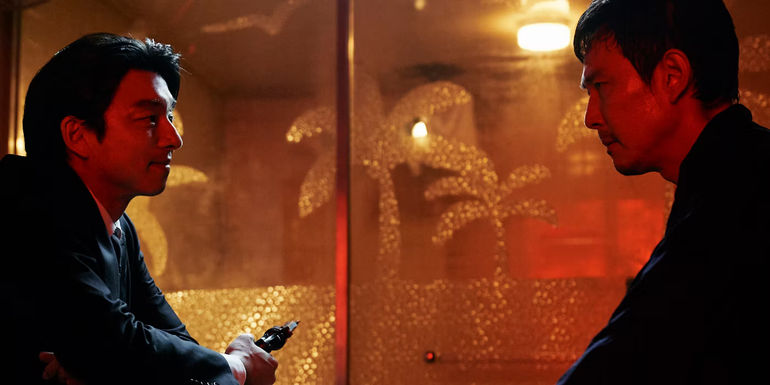 The Salesman holding a gun talking to Gi-hun in Squid Game season 2