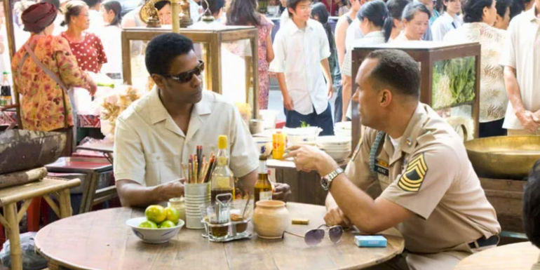 Denzel Washington and Roger Guenveur Smith talking and sitting at a table in American Gangster