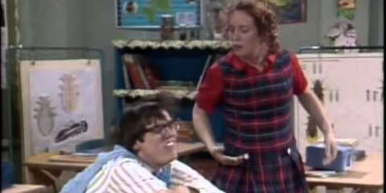 Parnell (Jim Carrey) with his head on the desk while Edna (Kelly Coffield) yells at him in In Living Color.