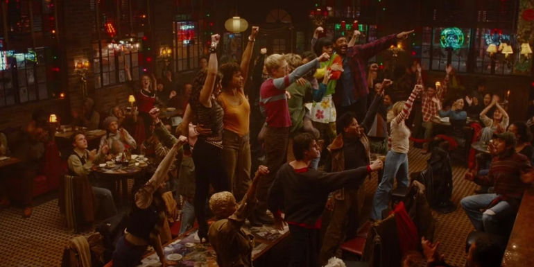 Cast of Rent standing on the table with their fists in the air